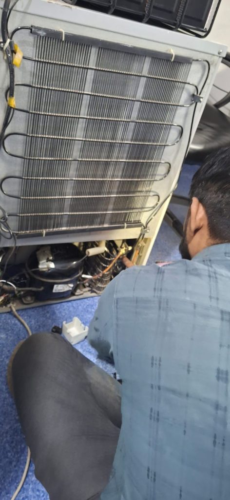 Technician repairing refrigerator compressor coils and checking for gas leakage.
