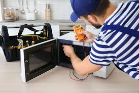 Technician testing microwave oven electrical components using a multimeter.