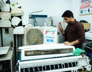 JJ Service & Solutions technicians repairing multiple appliances, including refrigerators, ACs, and microwaves, in their workshop.